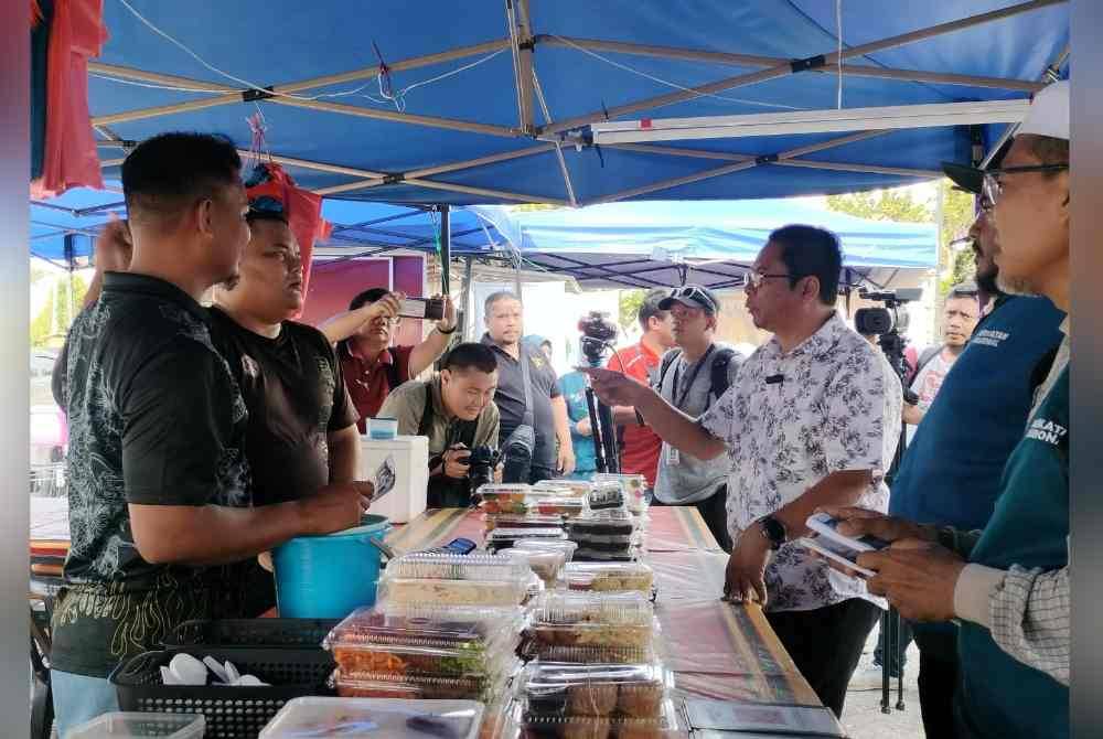 Abidin (dua kanan) semasa turun menyantuni peniaga di Simpang Ampat, Sungai Bakap pada Isnin.