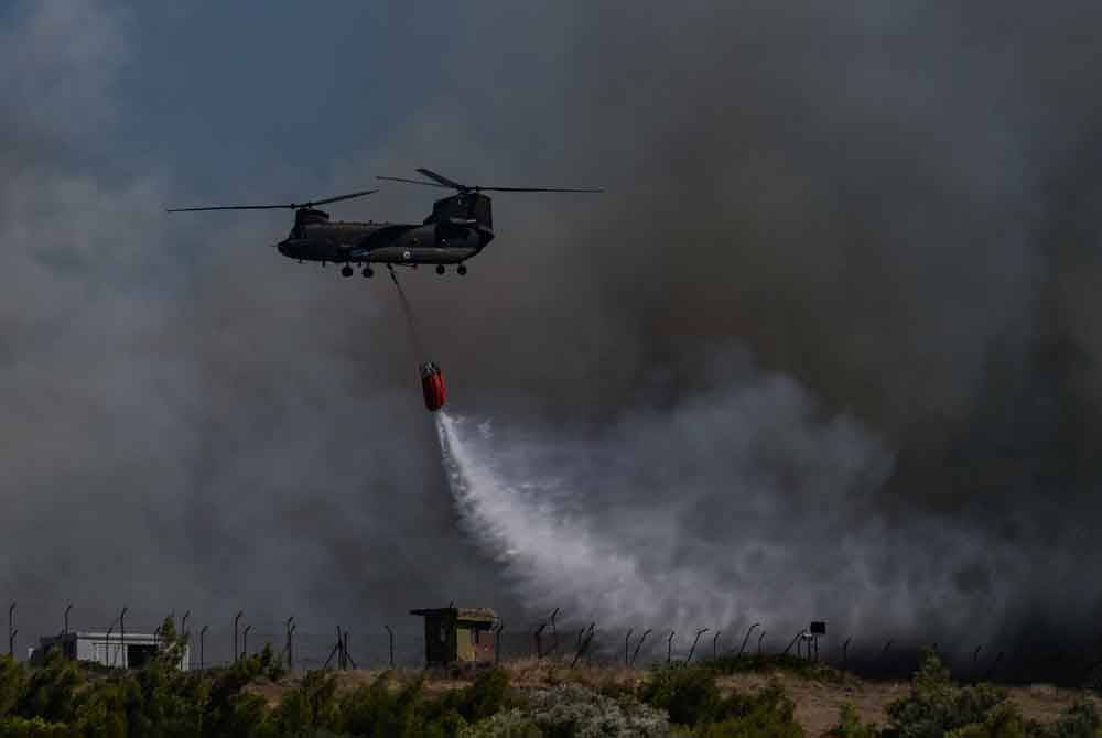 Sebuah helikopter Chinook menyembur air di kawasan kem tentera udara di Keratea.