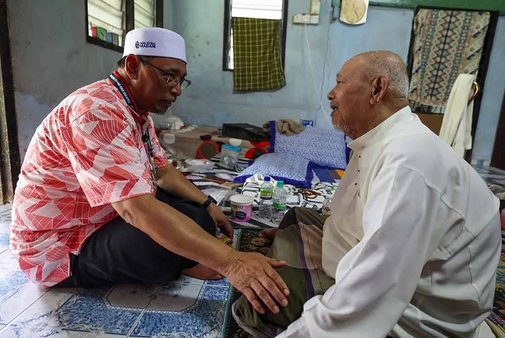 Joohari (kiri) beramah mesra dengan Che Dan Razak, 85, ketika bertemu pengundi di Kampung Sungai Buaya pada Isnin. Foto Bernama