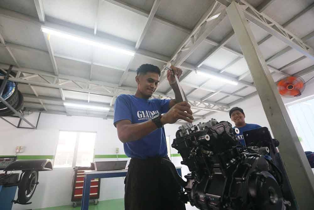 Pelatih GiatMara membaiki enjin motosikal di Pusat Kecemerlangan Industri Teknologi Modenas dan Kawasaki yang diwujudkan di GiatMara Pendang.