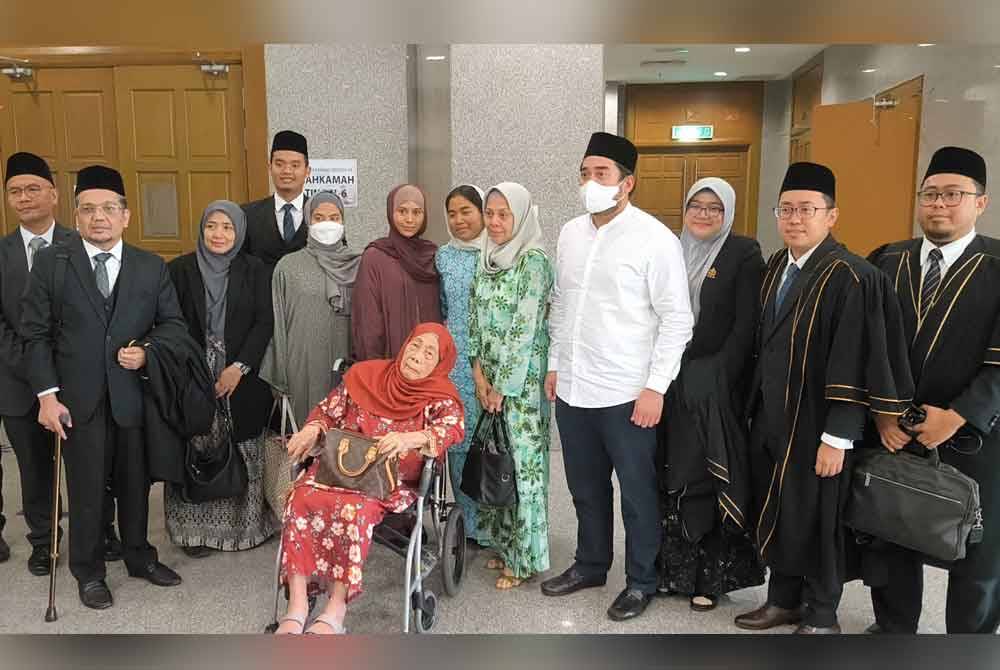 Selepas prosiding selesai, Kalsom (lima dari kanan) bersama empat anaknya serta ibu mentua, Aminah (berkerusi roda) bergambar bersama barisan peguam syarie, di Mahkamah Tinggi Syariah Wilayah Persekutuan di sini pada Rabu.
