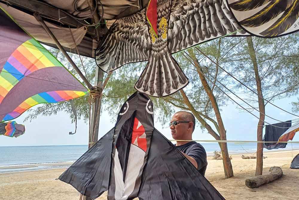 Roslan sedang mengikat layang-layang ikan paus di gerai miliknya di Pantai Sepat di sini pada Rabu.