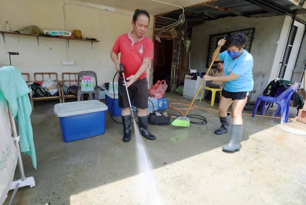 Sukarelawan daripada “Broom Amy” Christepher Suis,53, (kiri) bersama rombongannya bergotong royong membersihkan banjir lumpur di rumah mangsa banjir, seorang OKU, Francis Xavier yang terjejas akibat banjir kilat Ahad lalu di Kampung Dabak Penampang. Foto Bernama