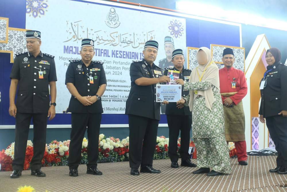 Abdul Aziz menyampaikan hadiah kepada salah seorang pemenang di Majlis Ihtifal Kesenian Islam Perujian Menghafaz Al-Quran dan Pertandingan Marhaban Peringkat Penghuni Jabatan Penjara Malaysia. Foto Jabatan Penjara Malaysia