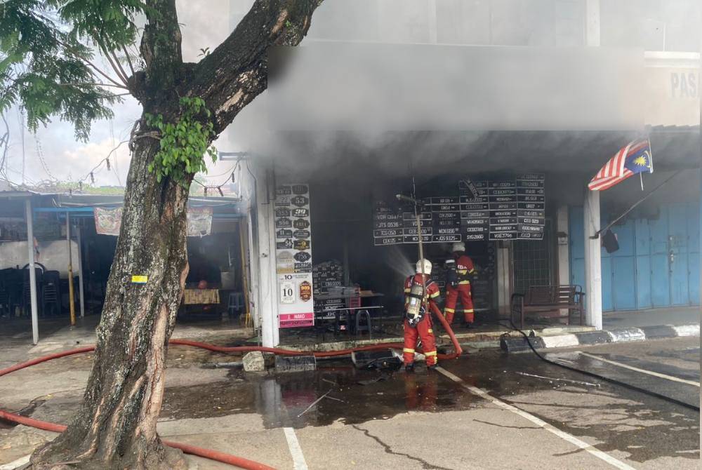 Anggota bomba membantu memadam kebakaran melibatkan kedai menjual plat kenderaan di Jalan Bukit Ubi di sini pada Jumaat.