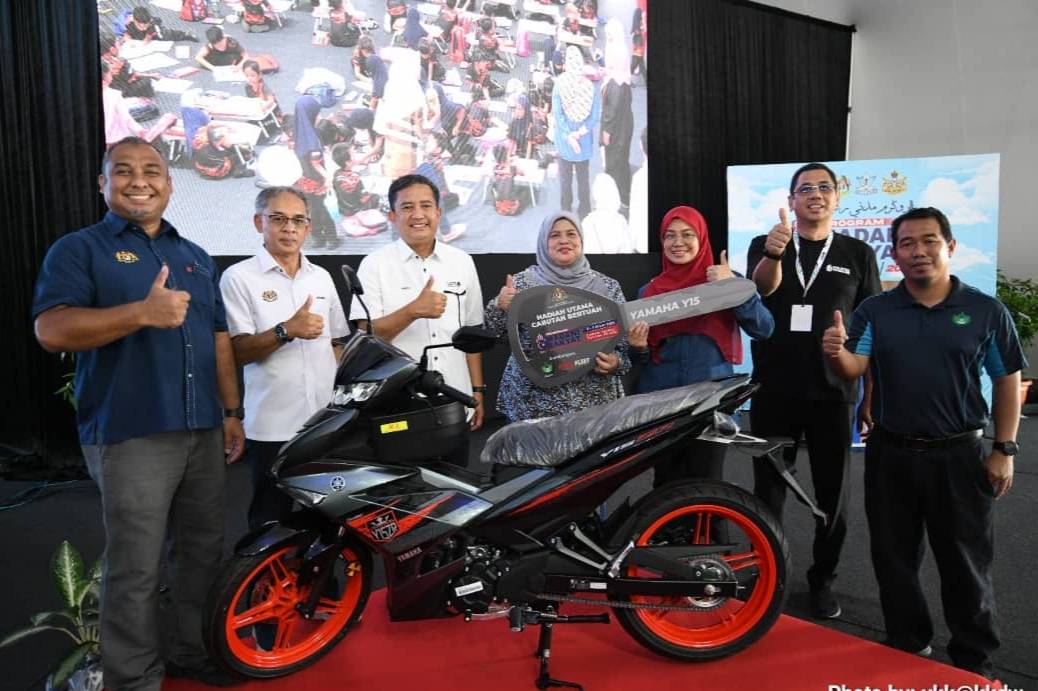 Rubiah (empat dari kanan) menyerahkan motosikal jenis Yamaha Y15ZR bernilai RM10,000 sumbangan RISDA Fleet Sdn Bhd untuk hadiah cabutan bertuah.