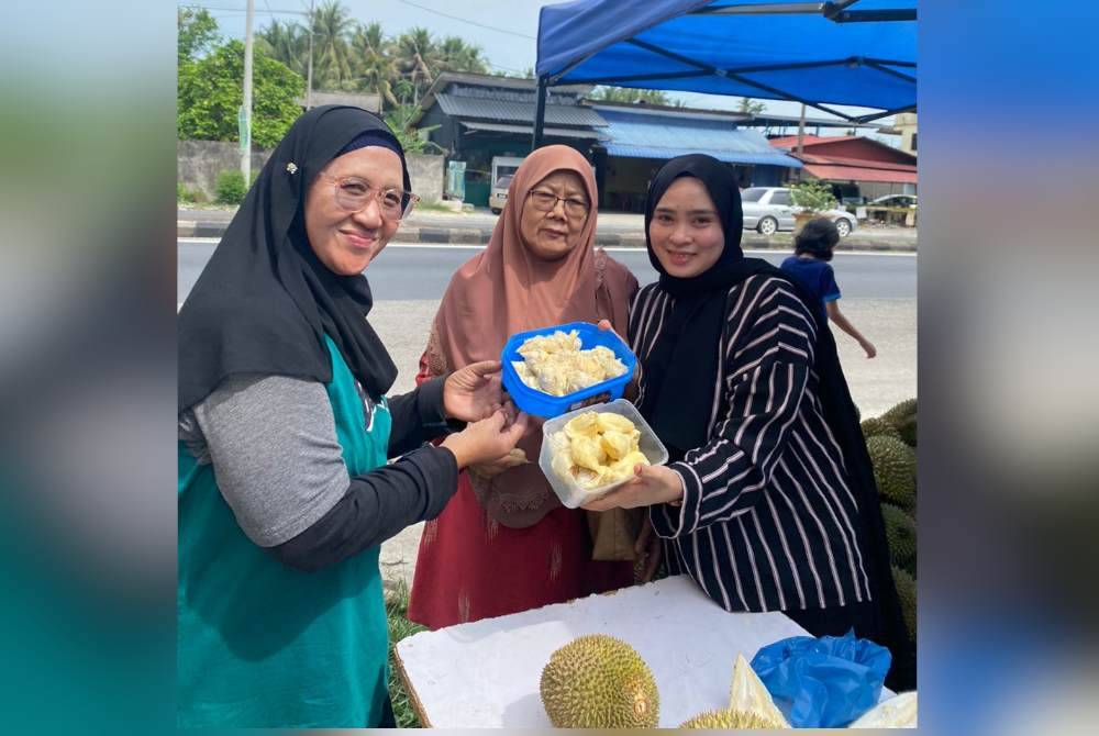 Siti Noor Fazera (kanan) bersama pelanggan yang membeli durian.
