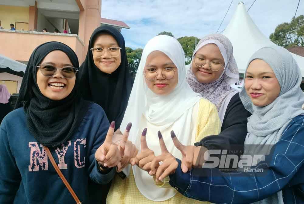 Dari kiri; Nur Athirah, Nur Afiqah Syamimi, Hana Humaira, Farah Farhana dan Amirah Syakirah menunjukkan jari yang dicelup dakwat biru selepas selesai mengundi di Sekolah Kebangsaan Sungai Bakap pada Sabtu.
