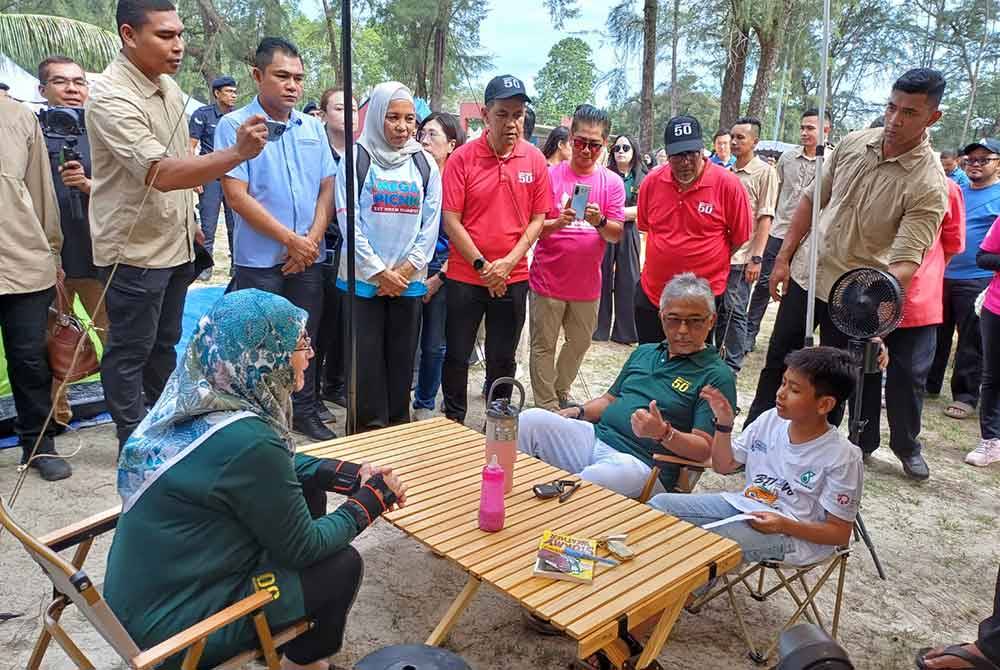 Tunku Azizah dan Al-Sultan Abdullah beramah mesra dengan salah seorang anak kepada alumni MRSM yang hadir pada Majlis Mega Picnic sempena sambutan 50T MRSM Kuantan di Taman Gelora pada Sabtu.