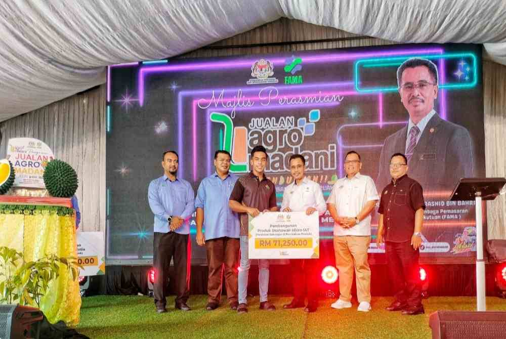 Abdul Rashid (empat, kiri) menyampaikan geran Pembangunan Produk Usahawan Micro IAT kepada salah seorang penerima.