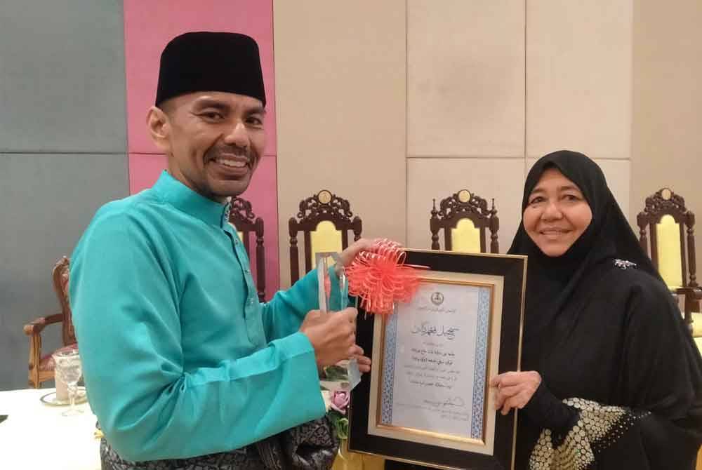 Noor Mazlina bersama anaknya, Mohd Shahir Mohd Yaziz, 42, menunjukkan hadiah yang diterima bagi Anugerah Siti Khadijah Sempena Sambutan Kemuncak Maal Hijrah Negeri Perak Tahun 1446H pada Ahad.
