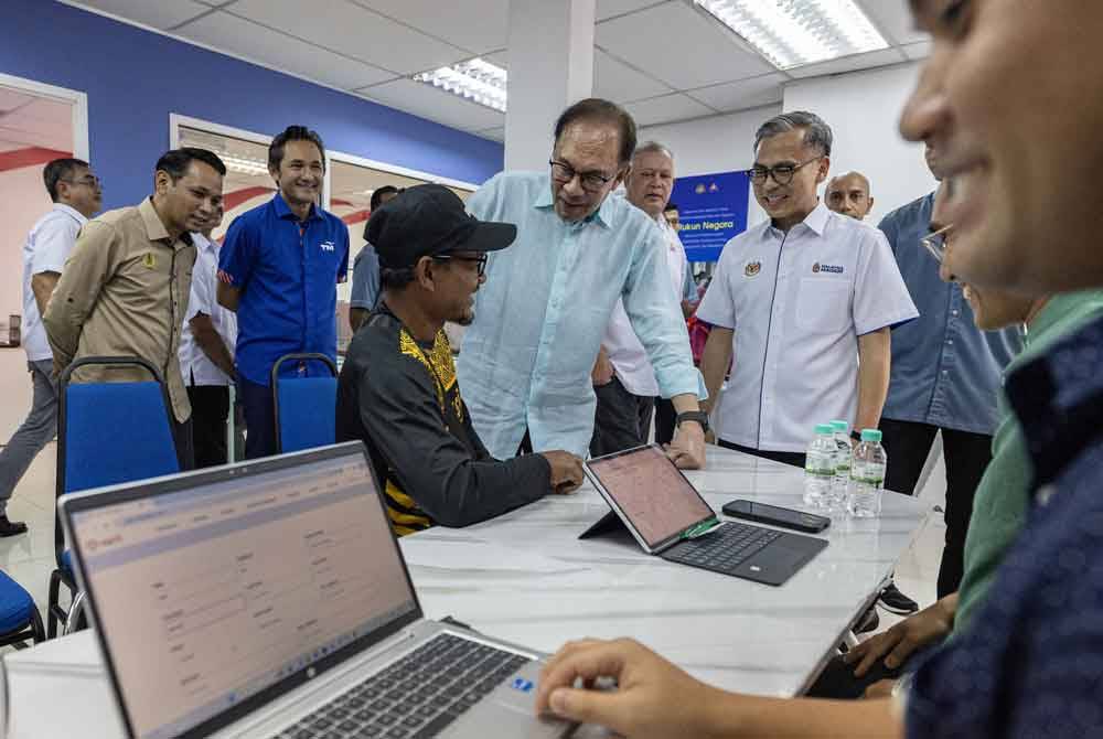 Anwar beramah mesra bersama penduduk setempat ketika meninjau Pusat Perkhidmatan Pintar Pusat Sebaran Maklumat Nasional (NADI) di NADI Kampung Dato’ Ahmad Said Manjoi, pada Isnin. Turut hadir, Fahmi. Foto Bernama