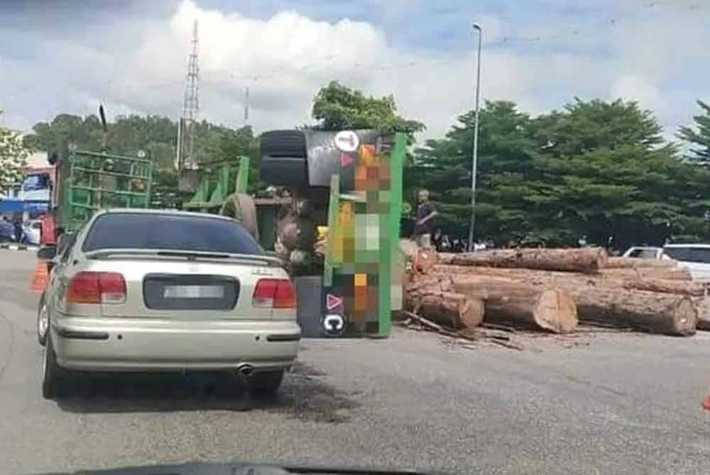 Lori membawa muatan kayu balak terbalik ketika mengambil selekoh.