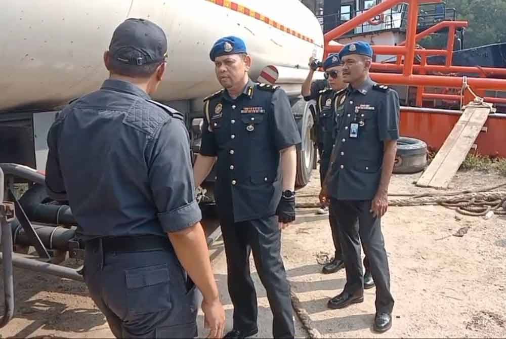 Saharuddin (tengah) memeriksa lori tangki yang dirampas KPDN Terengganu.