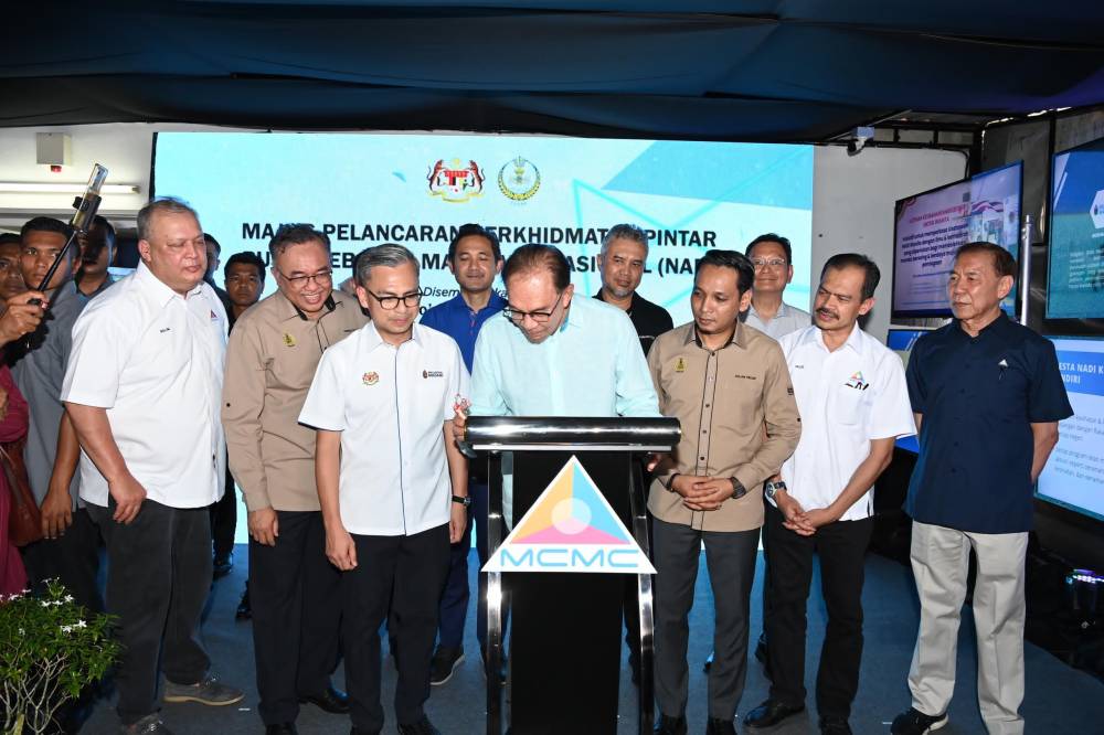 Anwar (tengah) menandatangani plak perasmian NADI Kampung Dato' Ahmad Said Tambahan 2.