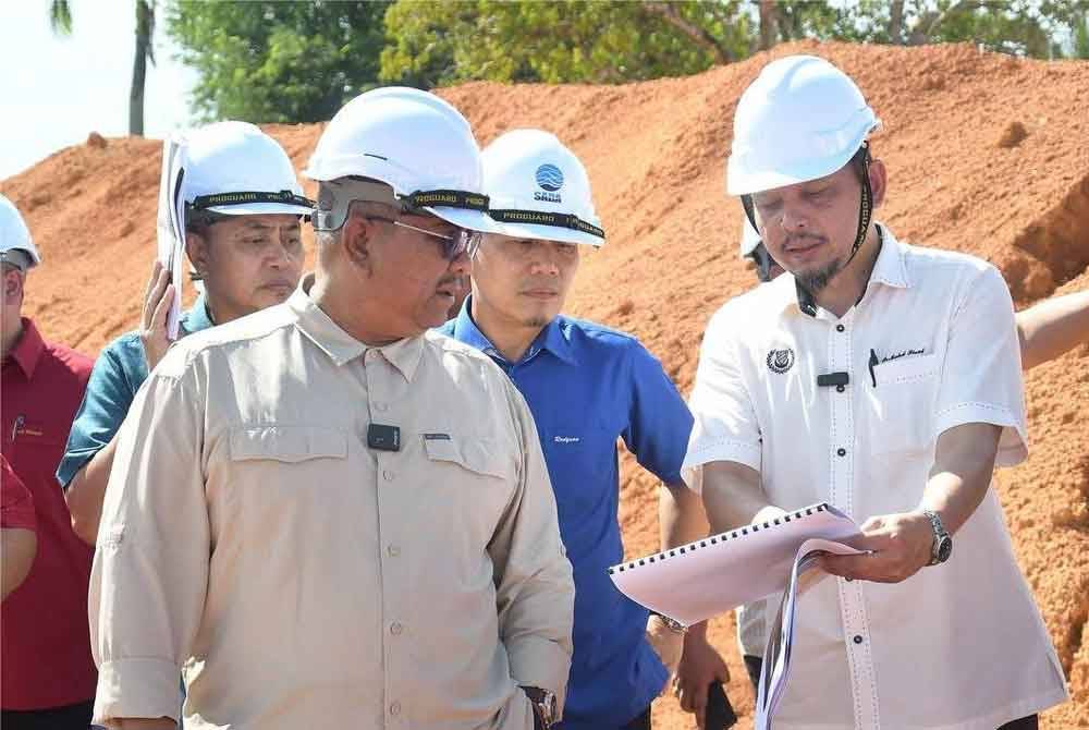 Sanusi (kiri) mendengar taklimat berkaitan kemajuan projek ketika meninjau LRA Sungai Limau dan LRA Bukit Selambau pada Selasa.
