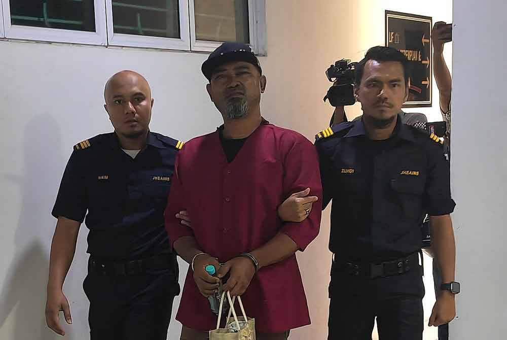 Norasid diiring penguat kuasa JHEAINS ketika hadir ke mahkamah.