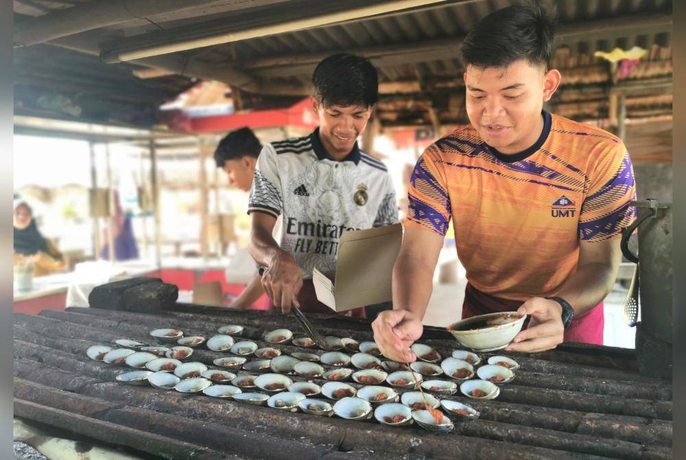 Pekerja gerai lokan bakar di Dataran Batu Putih menyediakan lokan yang ditempah pelanggan.