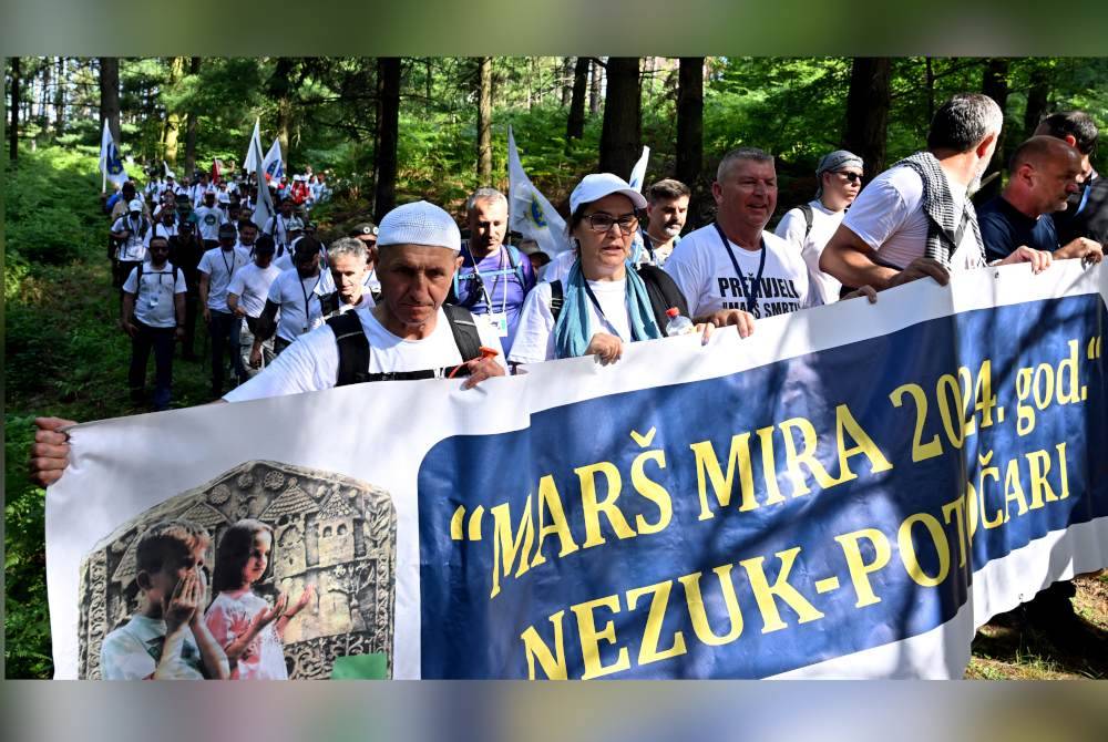 Penunjuk perasaan memegang sepanduk dibaca 'Mars Mira' atau 'Perarakan Keamanan' semasa berarak di hutan di kampung Nezuk, timur Bosnia Herzegovina.