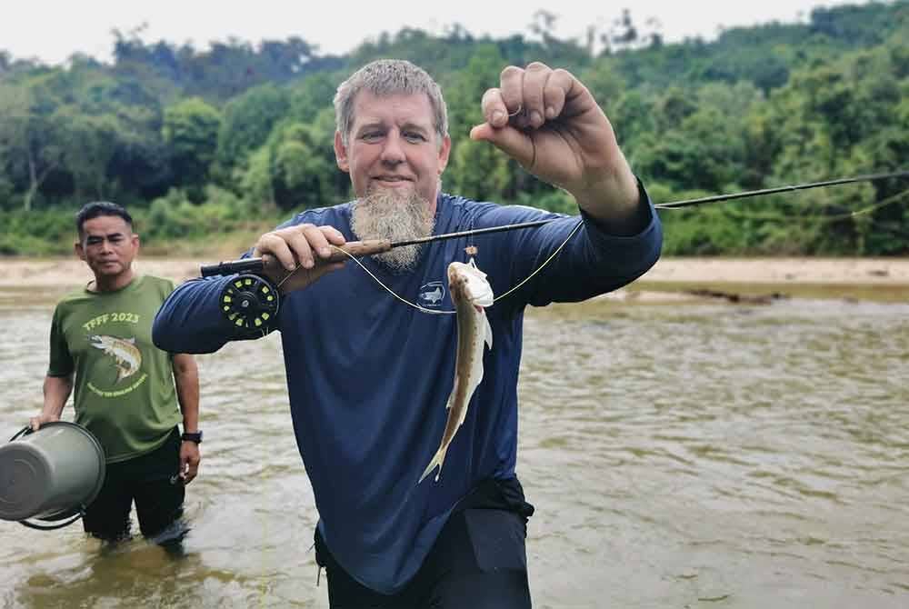Christopher (kanan) menunjukkan ikan sikang yang berjaya ditangkap di Sungai Berang dalam tempoh kurang 30 minit menggunakan teknik pancing layang.