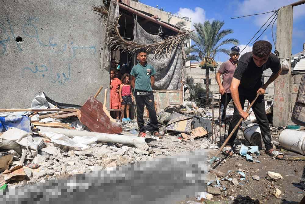 Seorang pemuda membersihkan sisa darah di hadapan sebuah rumah yang dibedil rejim Zionis.