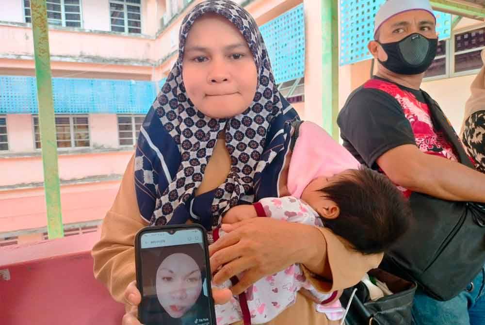 Faridah menunjukkan gambar kenangan arwah kakaknya, Allahyarham Azliha Ngah Ariffin di Hospital Melaka di sini, pada Isnin.