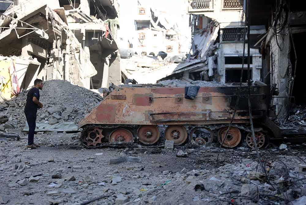 Seorang penduduk Palestin melihat kereta kebal tentera Israel yang musnah dibom pejuang Hamas di kejirana Shujaiya. Foto AFP