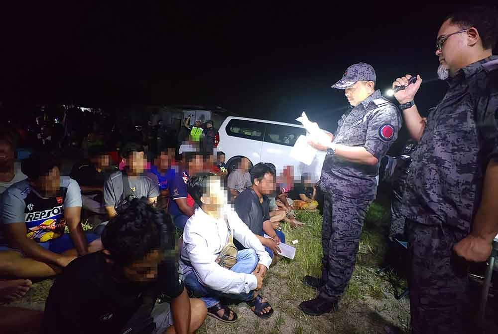 Kennith (kiri) memeriksa dokumen warga asing di sebuah penempatan haram yang diserbu di Taman Bandar Senawang