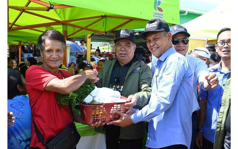 Mohamad (tengah) menyampaikan bakul sumbangan kepada salah seorang penerima ketika mengadakan lawatan ke Pasar Tamu.