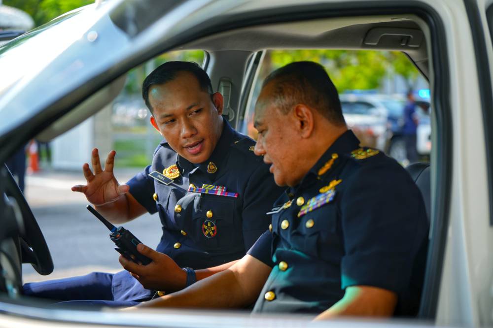 Rospiagos (kanan) mendengar penerangan daripada seorang pegawai JPJ berhubung teknologi digunakan pada kenderaan penguat kuasa yang baharu semasa majlis penyerahan di Bahagian Teknologi Digital JPJ, Cyberjaya pada Rabu. Foto JPJ