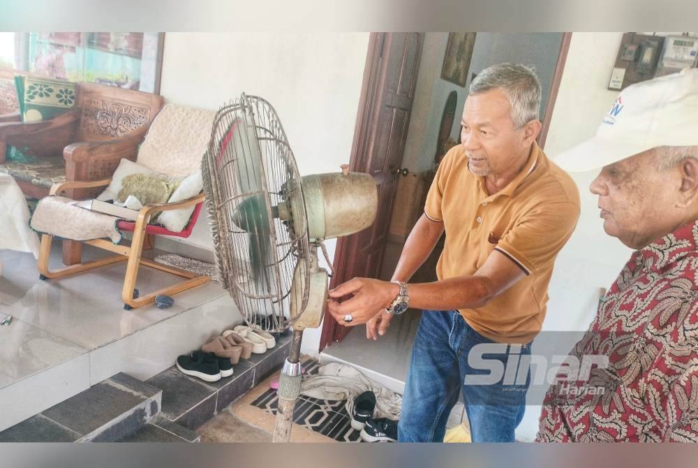 Abdul Rashid (kiri) menunjukkan kipas antik dipercayai berusia lebih 100 tahun yang masih boleh digunakan hingga kini.