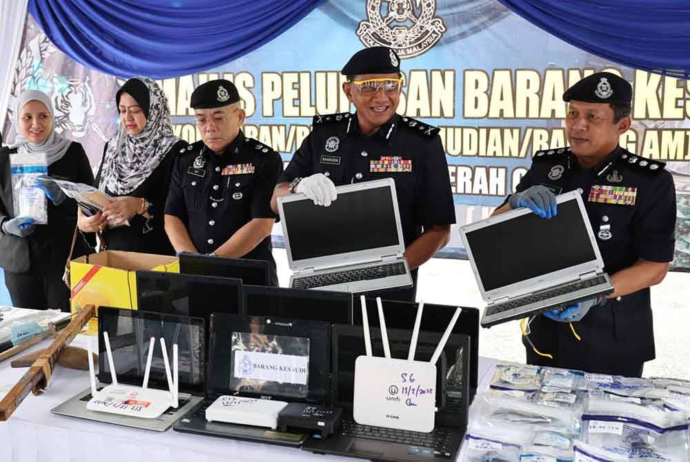 Noor Ariffin (kanan) dan Baharudin (dua dari kanan) menunjukkan antara barang kes yang dilupuskan pada Jumaat.