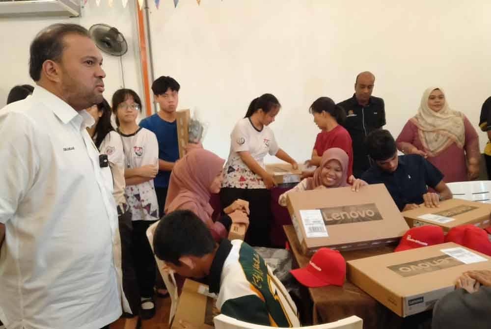 Iskandar Dzulkarnain (kiri) menyantuni pelajar cemerlang SPM sempena Majlis Penyampaian Komputer Riba Kepada Pelajar Cemerlang SPM di sebuah restoran pada Sabtu.