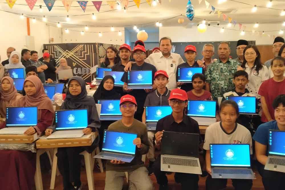 Iskandar Dzulkarnain (belakang, tengah) bersama-sama penerima komputer riba sempena Majlis Penyampaian Komputer Riba Kepada Pelajar Cemerlang SPM di sebuah restoran pada Sabtu.