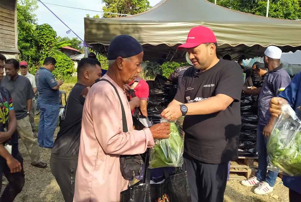 Iskandar Dzulkarnain (kanan) menyerahkan sayur yang telah dituai melalui projek rintis di Rumah Sayur Bendang Kering di sini pada Sabtu.