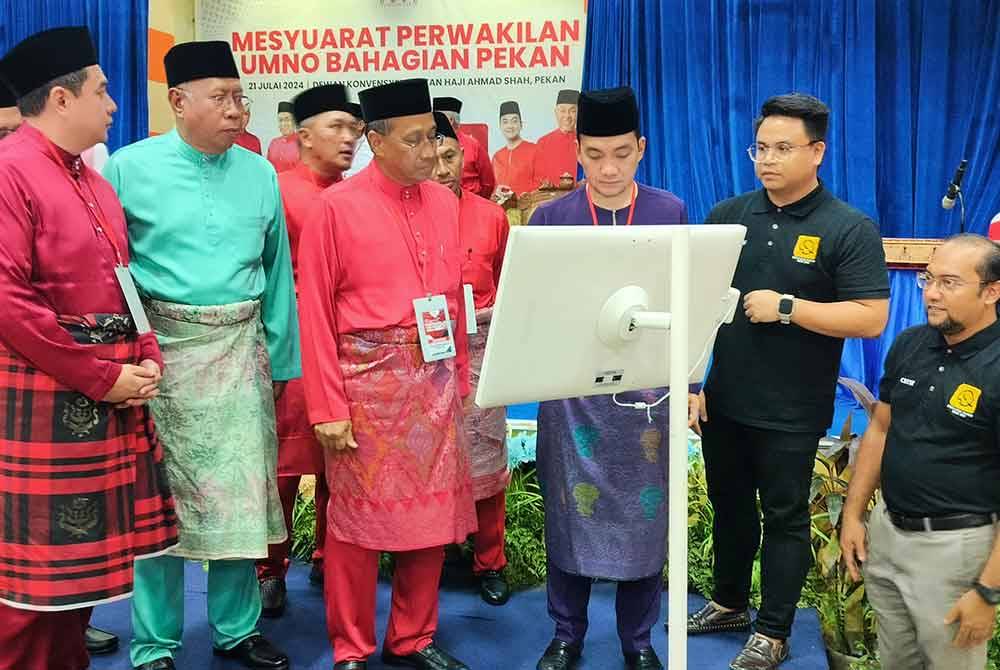 Mohammad Fakhruddin (tiga dari kiri) mengiringi Onn Hafiz (tiga dari kanan) menyempurnakan gimik pelancaran laman sesawang UMNO Pekan sempena Majlis Perasmian Mesyuarat Perwakilan UMNO Pekan di Dewan Konvensyen Sultan Ahmad Shah pada Ahad.