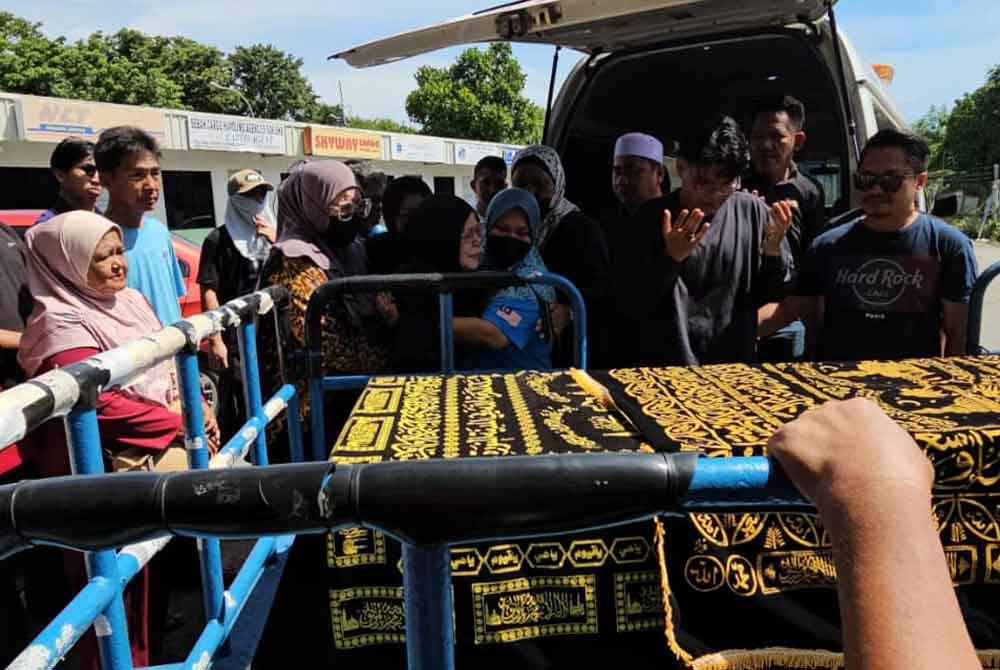 Mohd Shahzehanudin (dua dari kanan) abang kepada Allahyarham Mohd Rais menadah tangan sambil berdoa sebelum jenazah adiknya dipindahkan ke dalam van untuk dibawa ke Kota Belud bagi urusan pengebumian.