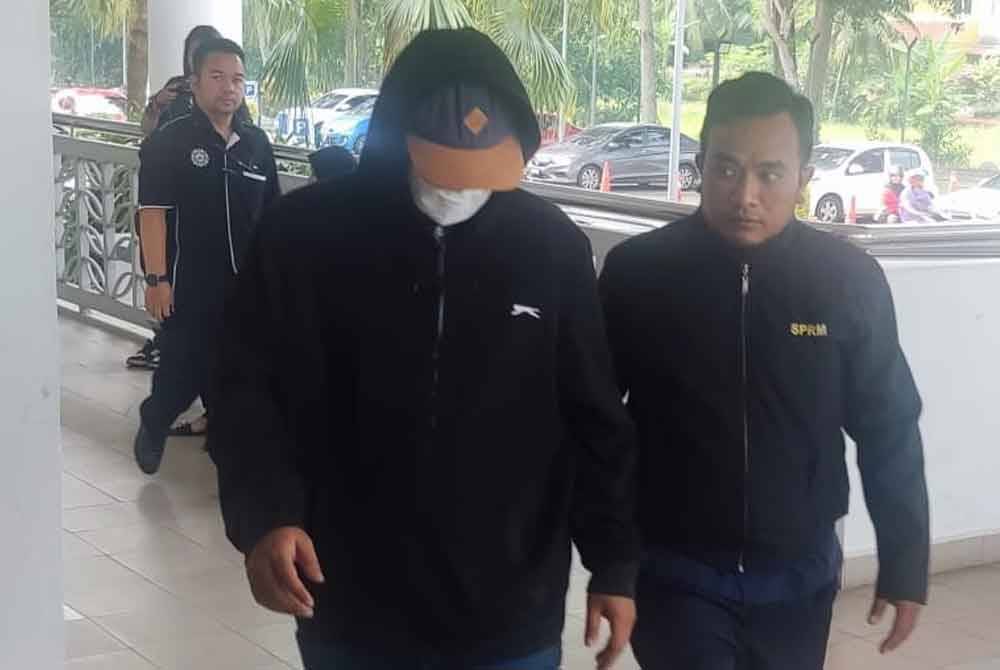 Tertuduh (dua dari kanan) diiringi pegawai SPRM untuk membayar ikat jamin selepas dituduh di Mahkamah Sesyen Alor Setar, pada Isnin.