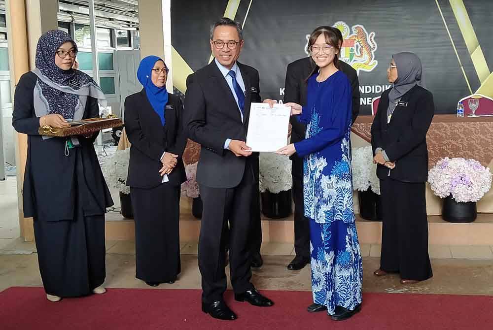 Mohamad Fauzi (tiga dari kiri) menyampaikan slip keputusan peperiksaan STPM kepada pelajar cemerlang selepas Majlis Pengumuman Keputusan Peperiksaan STPM Negeri Perak di Jabatan Pendidikan Negeri Perak pada Selasa.