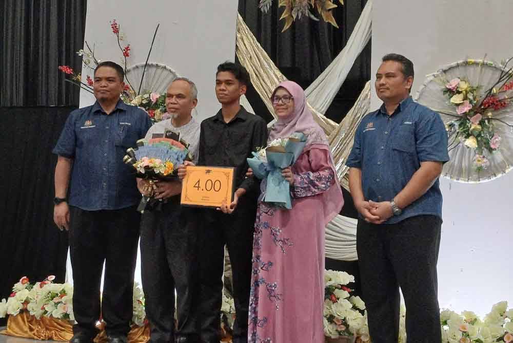 Ammar (tengah) bersama ibu dan bapanya menerima kalungan bunga pada majlis penyampaian calon cemerlang STPM di SMK Astana pada Selasa.