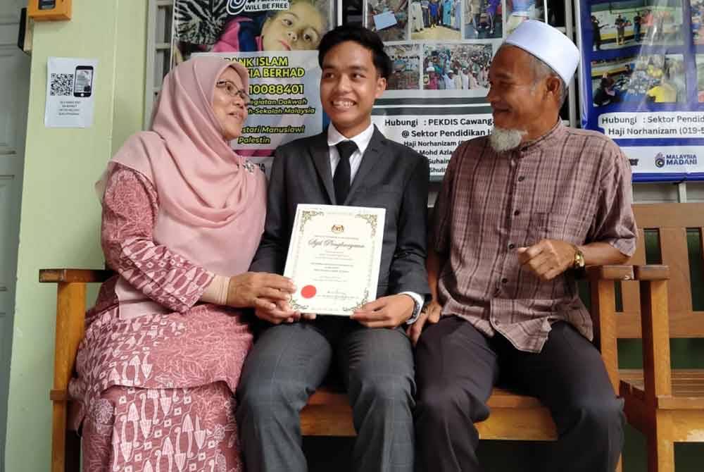 Muhammad Iqhfaz Hasif (tengah) bersama kedua orang tuanya selepas menerima keputusan cemerlang sempena Majlis Pengumuman Keputusan Peperiksaan STPM Negeri Perak di Jabatan Pendidikan Negeri Perak di sini pada Selasa.