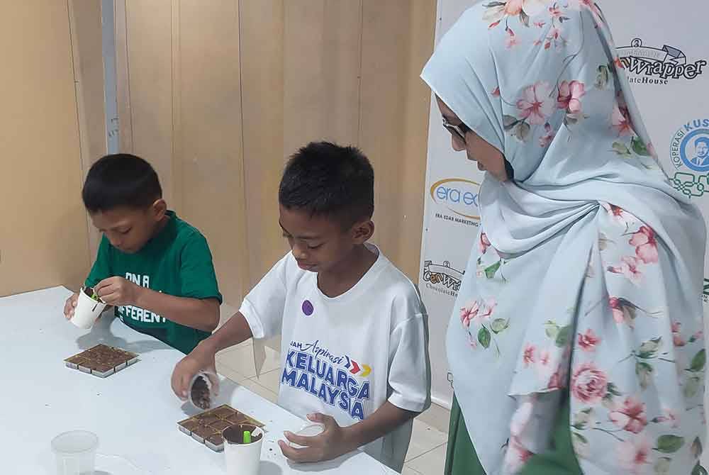 Aishah (kanan) melihat pengunjung kanak-kanak melakukan aktiviti DIY coklat.