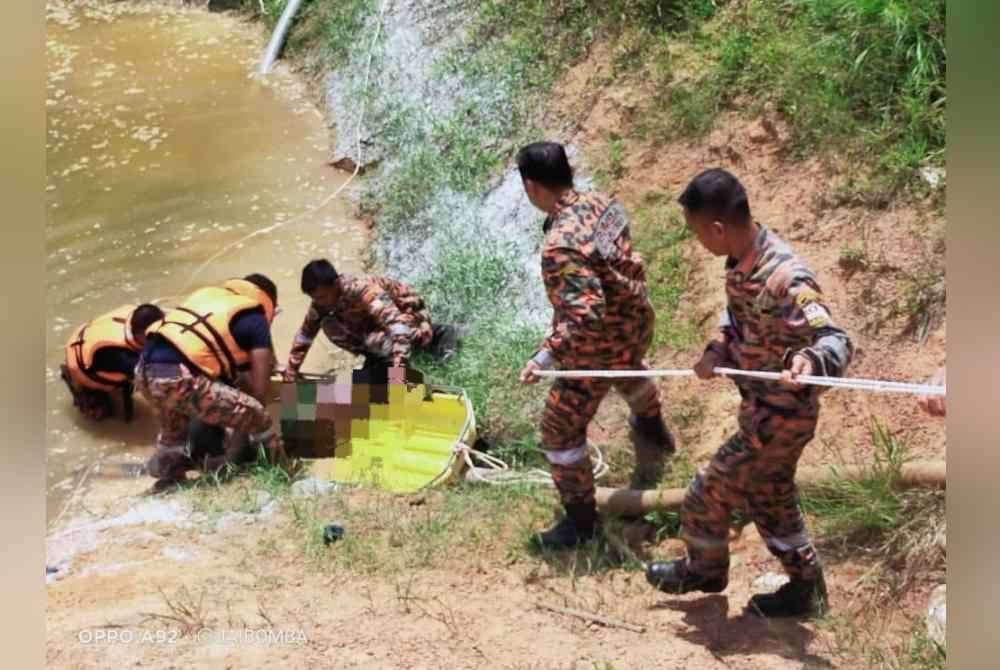 Anggota bomba mengangkat mayat mangsa yang ditemui lemas selepas tergelincir ke dalam kolam tadahan di Gersik pada Selasa. Foto bomba