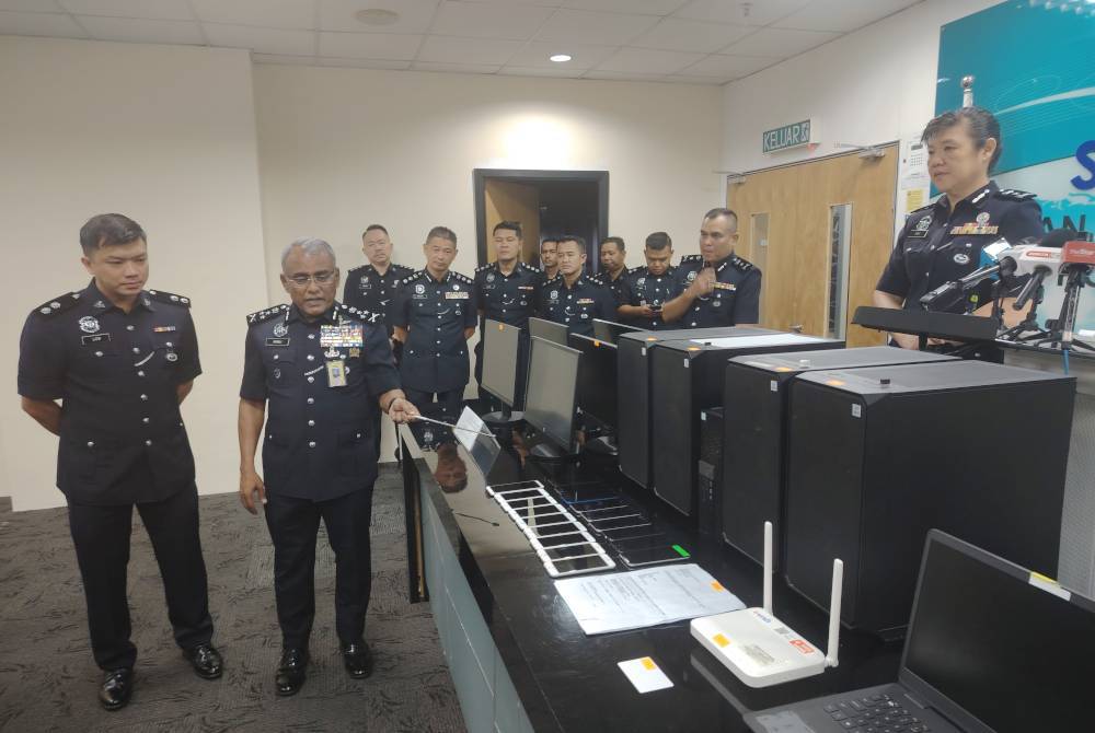 Ramli (dua kiri) menunjukkan antara rampasan barang kes susulan tumpasnya sindiket pusat pangilan tipu tawaran kerja di Sungai Besi, Kuala Lumpur Isnin lalu.