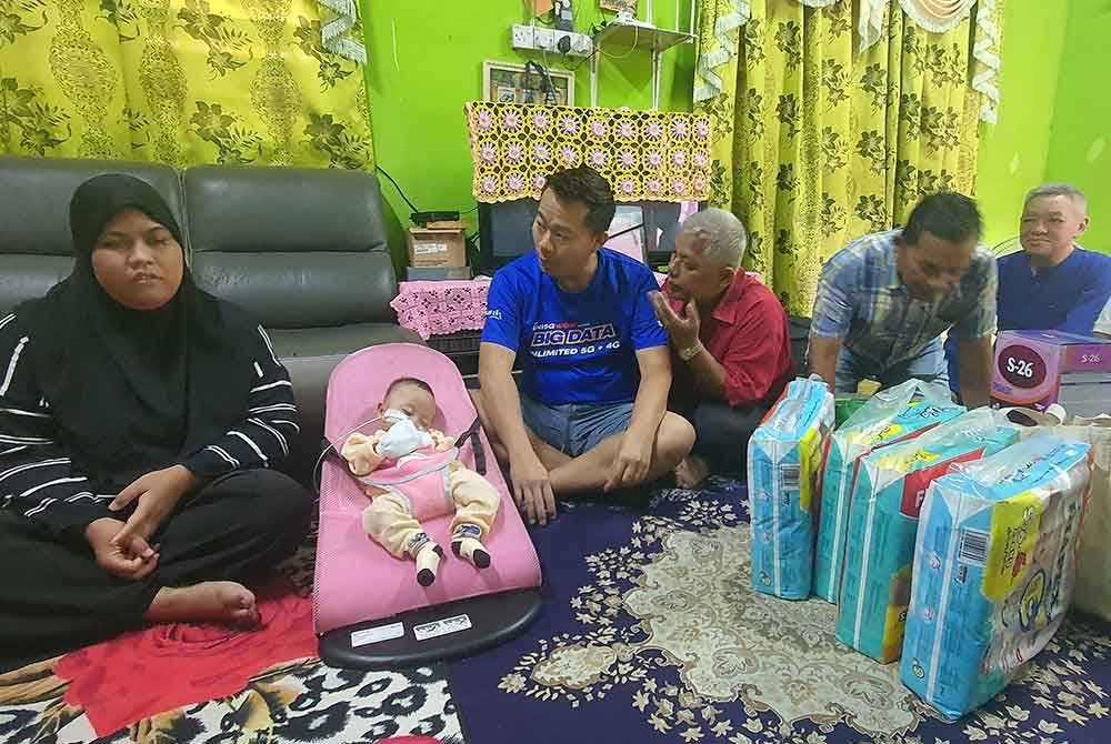 Quan Long (dua dari kiri) ketika menziarahi Nur Afiyah dan Nurul Amiza di kediaman mereka di Permatang Tok Gelam pada Khamis.