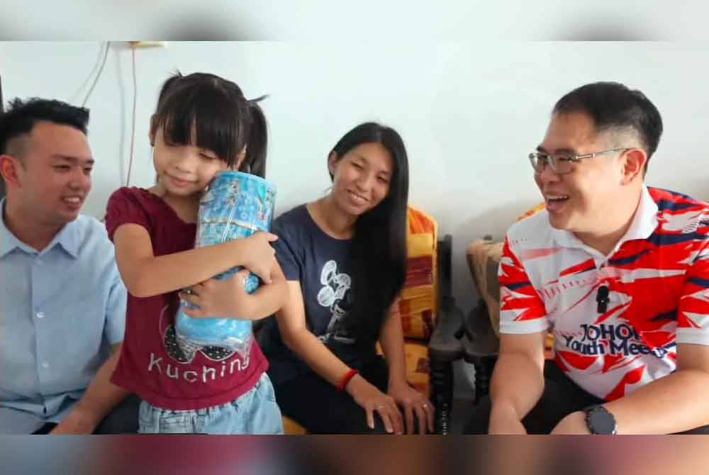 Albertine mendakap erat hadiah daripada menteri besar yang disampaikan oleh Tian Soon (kanan), pada Jumaat.