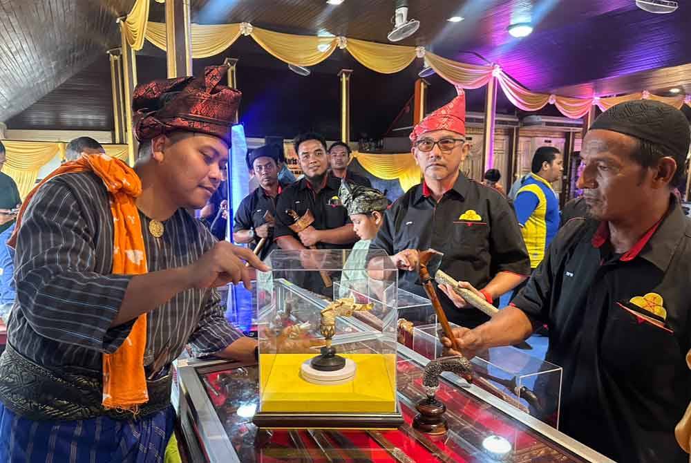 Peniaga keris, Mohd Aizal Azwan Amran (kiri) memberi penerangan berkait hulu keris jenis tanjong yang bernilai RM35,000.