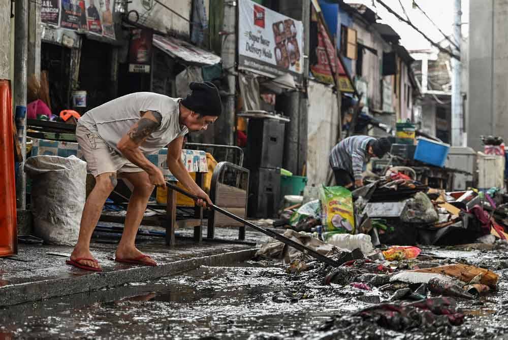 Penduduk membersihkan serpihan yang membanjiri rumah mereka selepas Taufan Gaemi melanda Manila. - AFP