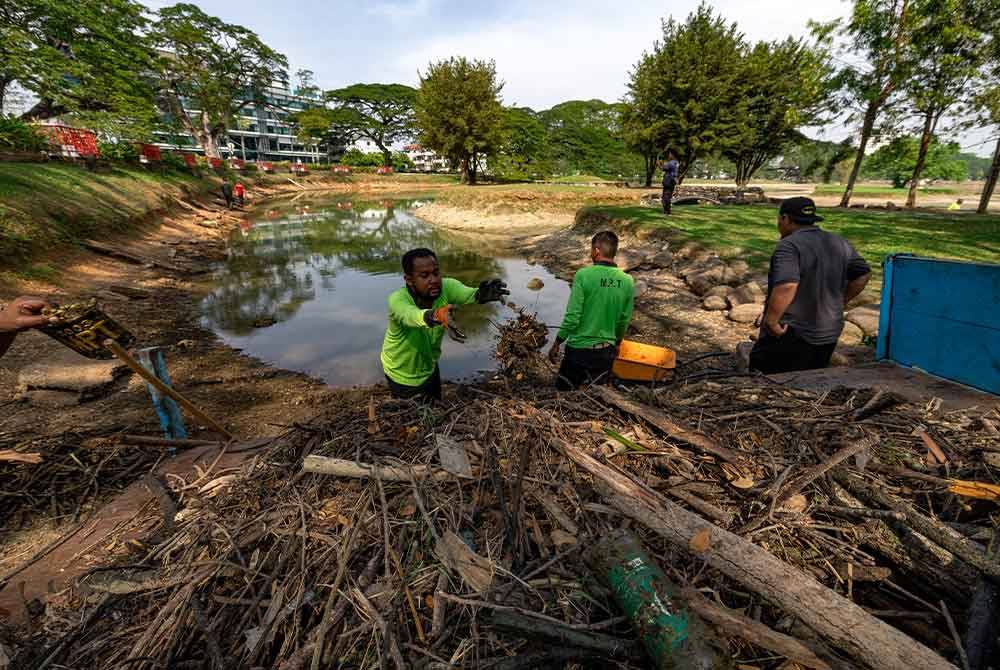 Petugas-petugas dilihat membersih di kawasan Taman Tasik Taiping yang kering. Foto Bernama