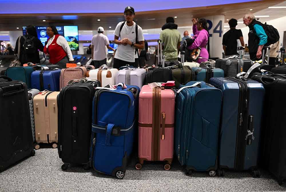 Pelanggan sedang berbaris menunggu pengesahan jadual penerbangan yang terjejas akibat gangguan IT di Lapangan Terbang Los Angeles. - AFP